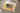 Auf einem Sofa liegt ein geschlossenes CEWE FOTOBUCH neben einem Kuscheltier und einer Decke. Auf dem Buchcover ist das Foto von drei kleinen Kindern abgebildet, die auf einer Wiese liegend nach oben in die Kamera lächeln. Der Titel lautet „Für Oma“. Ein gelber Aquarellfleck und florale Elemente bilden den Hintergrund der Titelseite.