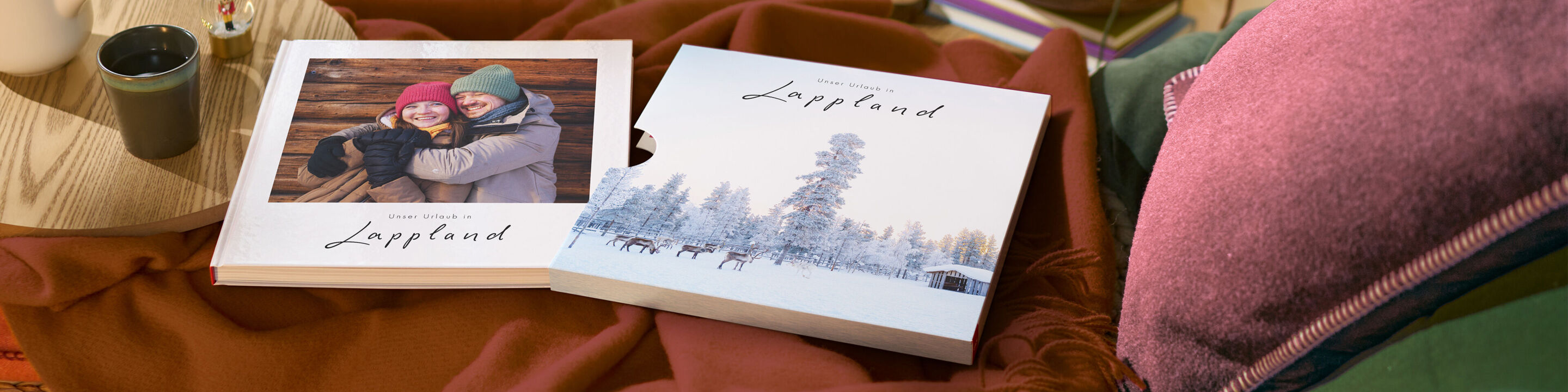 Ein winterlich gestaltetes CEWE FOTOBUCH mit Schuber liegt auf einem Tisch.