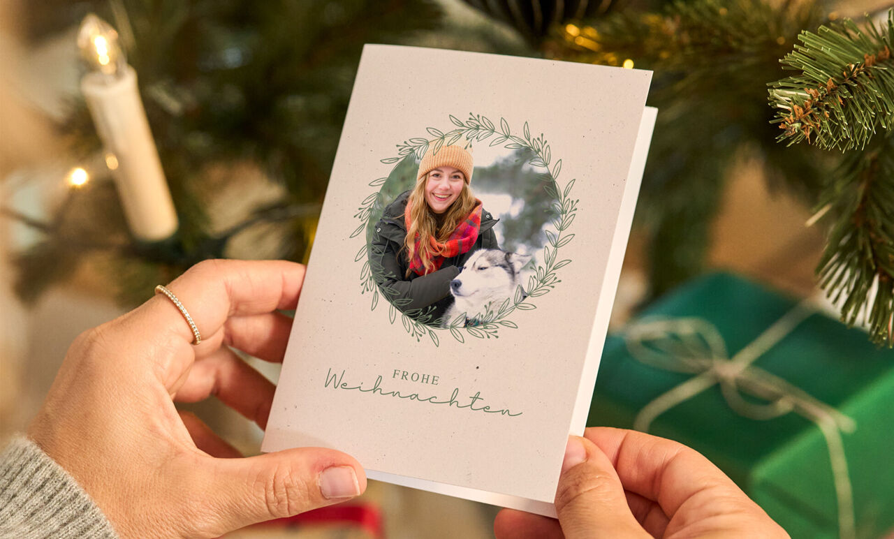 Person hält eine Weihnachtskarte mit Foto und Gruß.