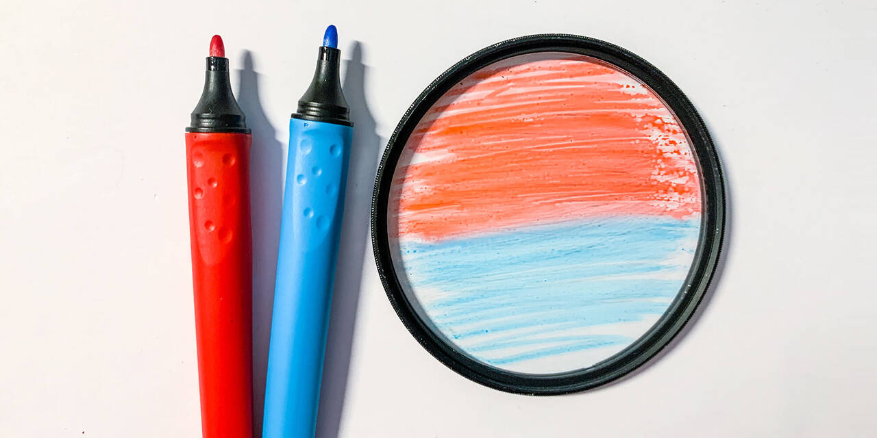 Auf dem Bild ist ein roter und ein blauer Stift zu sehen. Daneben liegt eine Linse, welche in der oberen Hälfte rot und in der unteren Hälfte blau angemalt ist.
